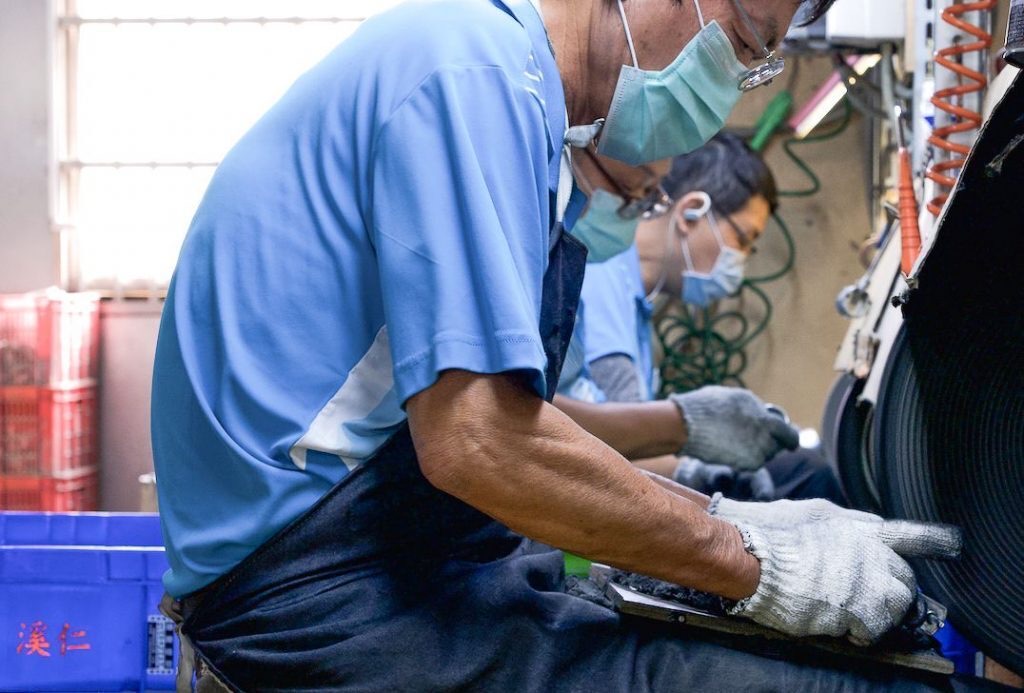 Craftspeople sanding metal parts by hand