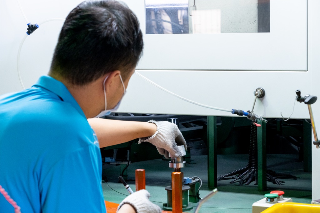A technician checking a machined metal part at a test station
