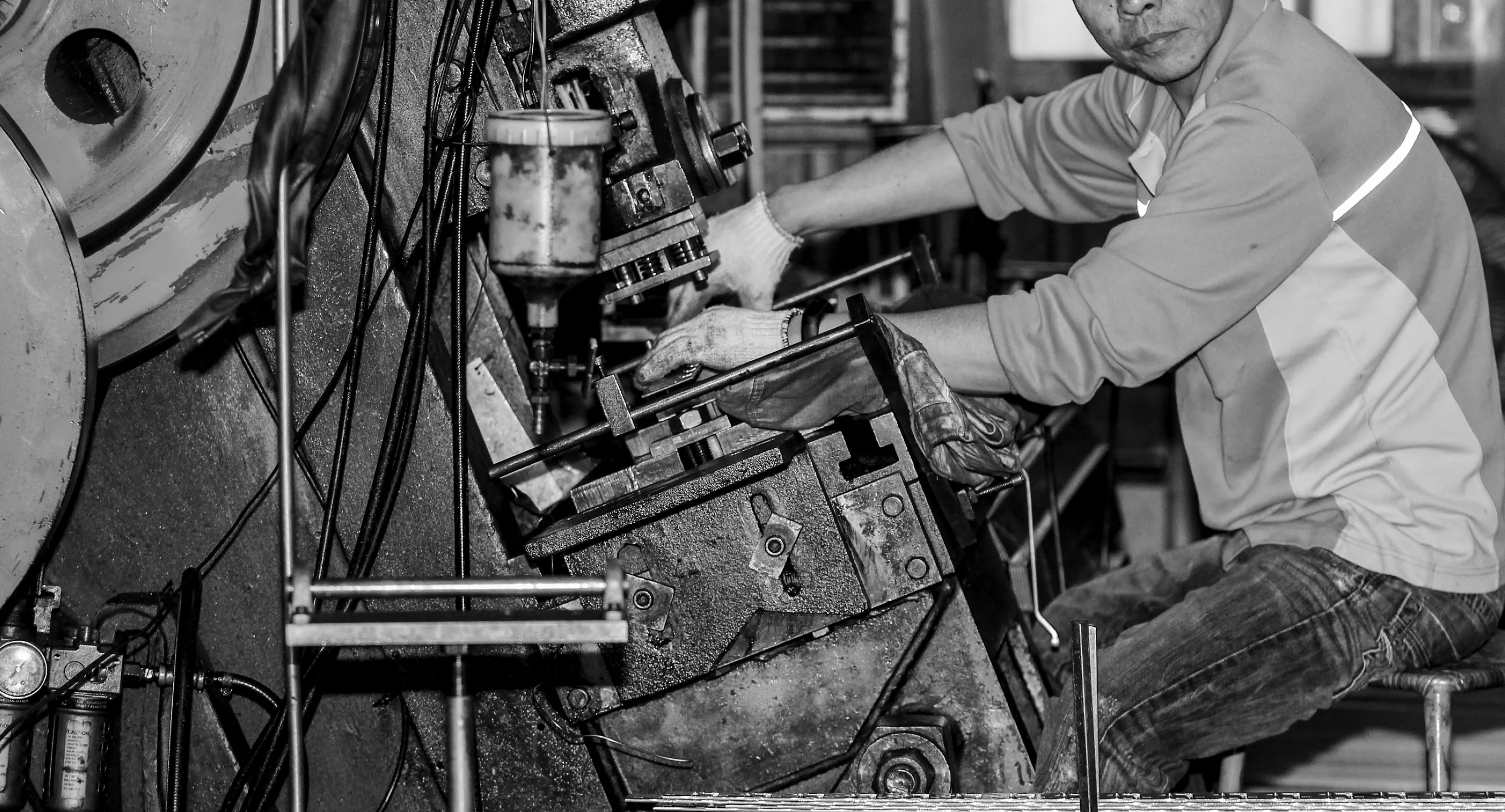Dicas worker operating a metal stamping press on the factory floor